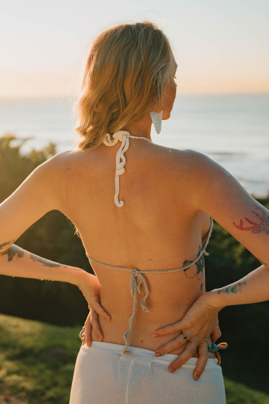 back view of the fitted scalloped crochet top, highlighting bust coverage and tie-back detail against an ocean backdrop.