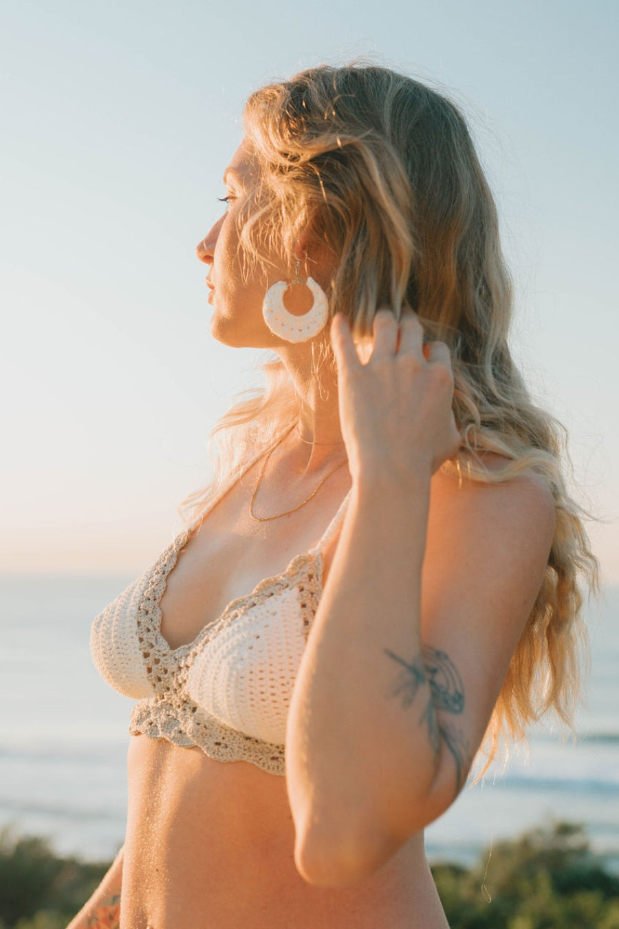 Side view of the fitted scalloped crochet top, highlighting bust coverage and white crochet matching earrings