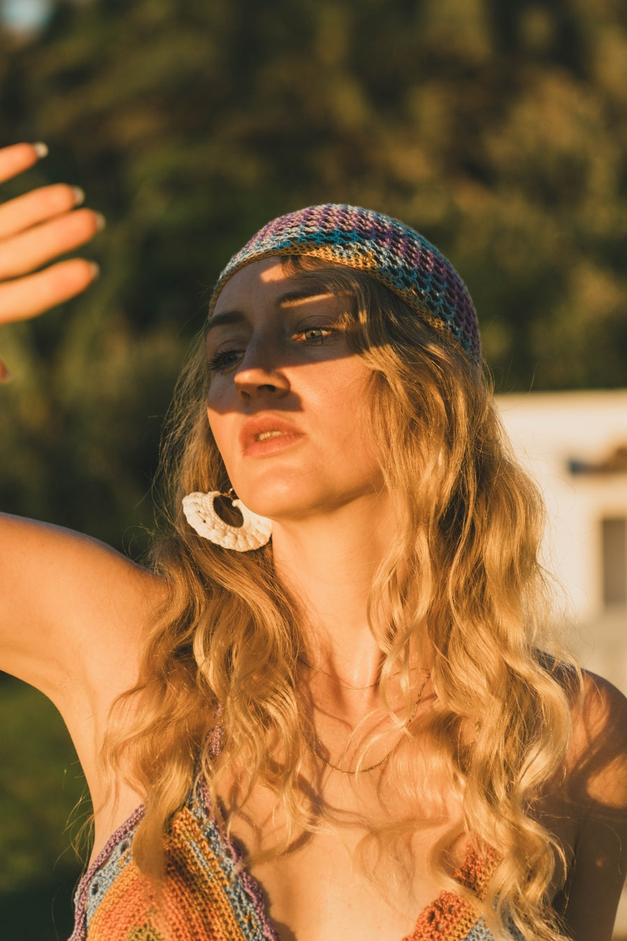 women wearing a rainbow-toned crochet cap with a snug crown fit, styled with a matching bikini top with her hand covering the sunlight.