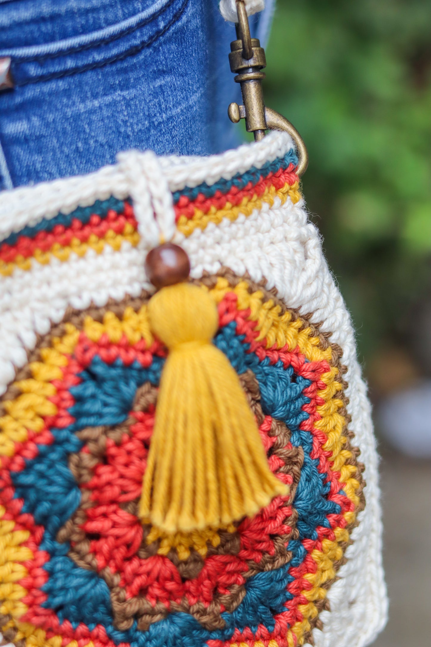 Colorful crocheted bag with a yellow tassel on a blurred background