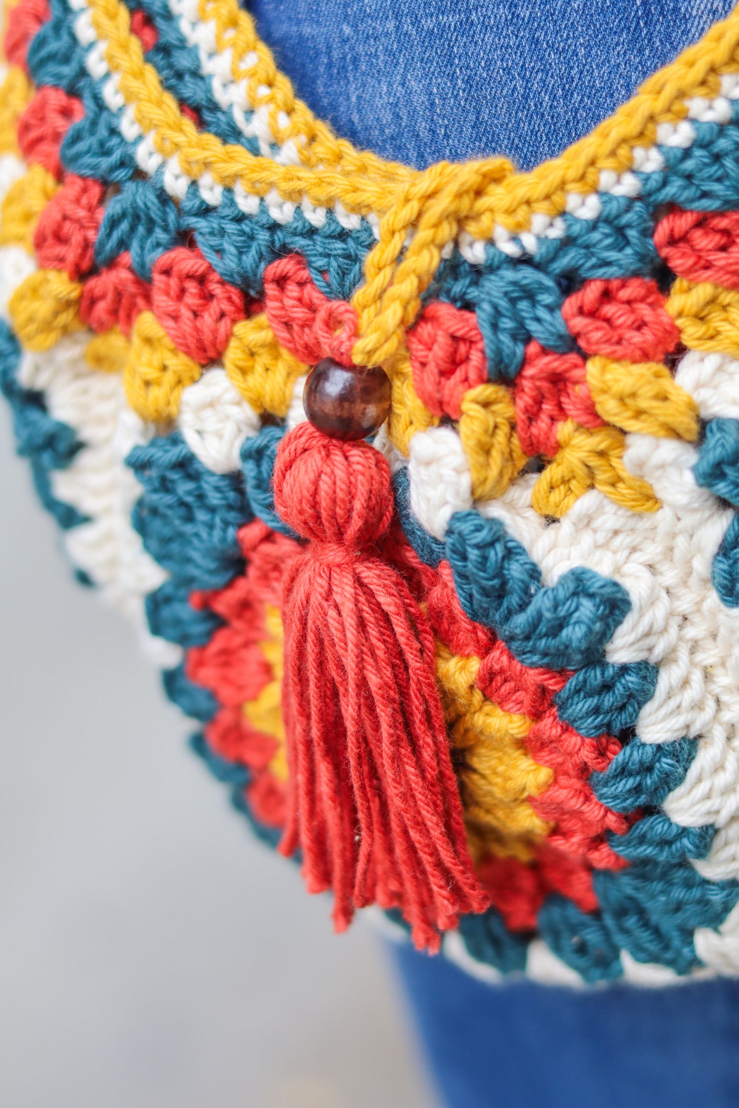 Colorful crocheted bag with a tassel on a blue background