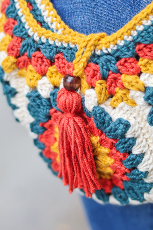 Colorful crocheted bag with a tassel on a blue background