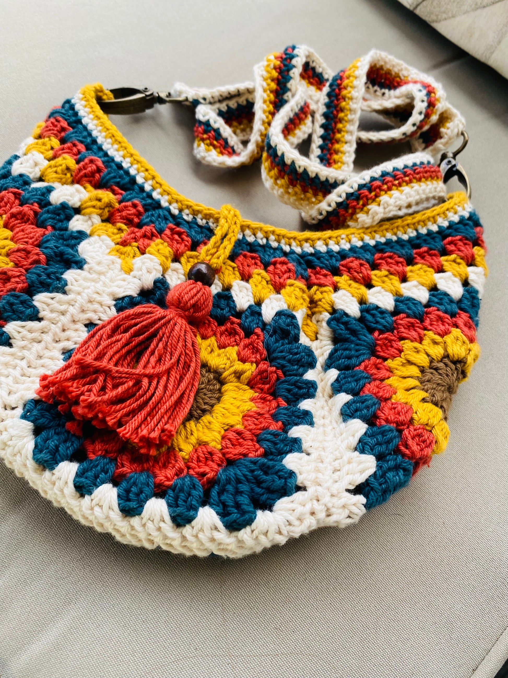 Colorful crocheted bag with a decorative tassel on a light gray surface